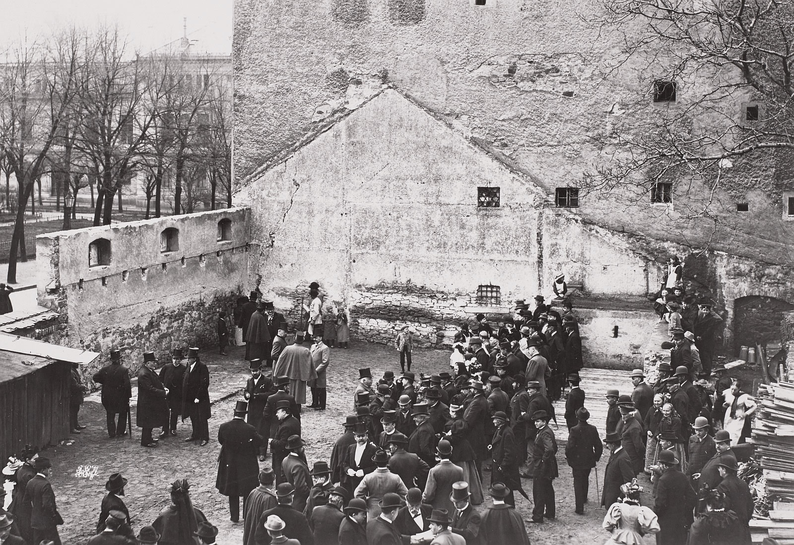 schwarz-weiß-Foto, auf dem eine Gruppe von Menschen zu sehen ist, umgeben von Resten einer Mauer