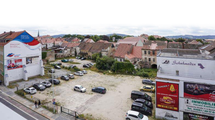 Foto aus der Vogelperspektive auf eine Anordnung von alten Gebäuden, die einen Parkplatz mit Autos säumen