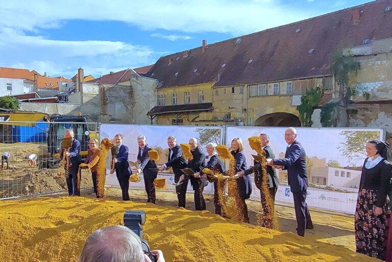 mehrere Personen mit Schaufeln werfen Sand in die Luft