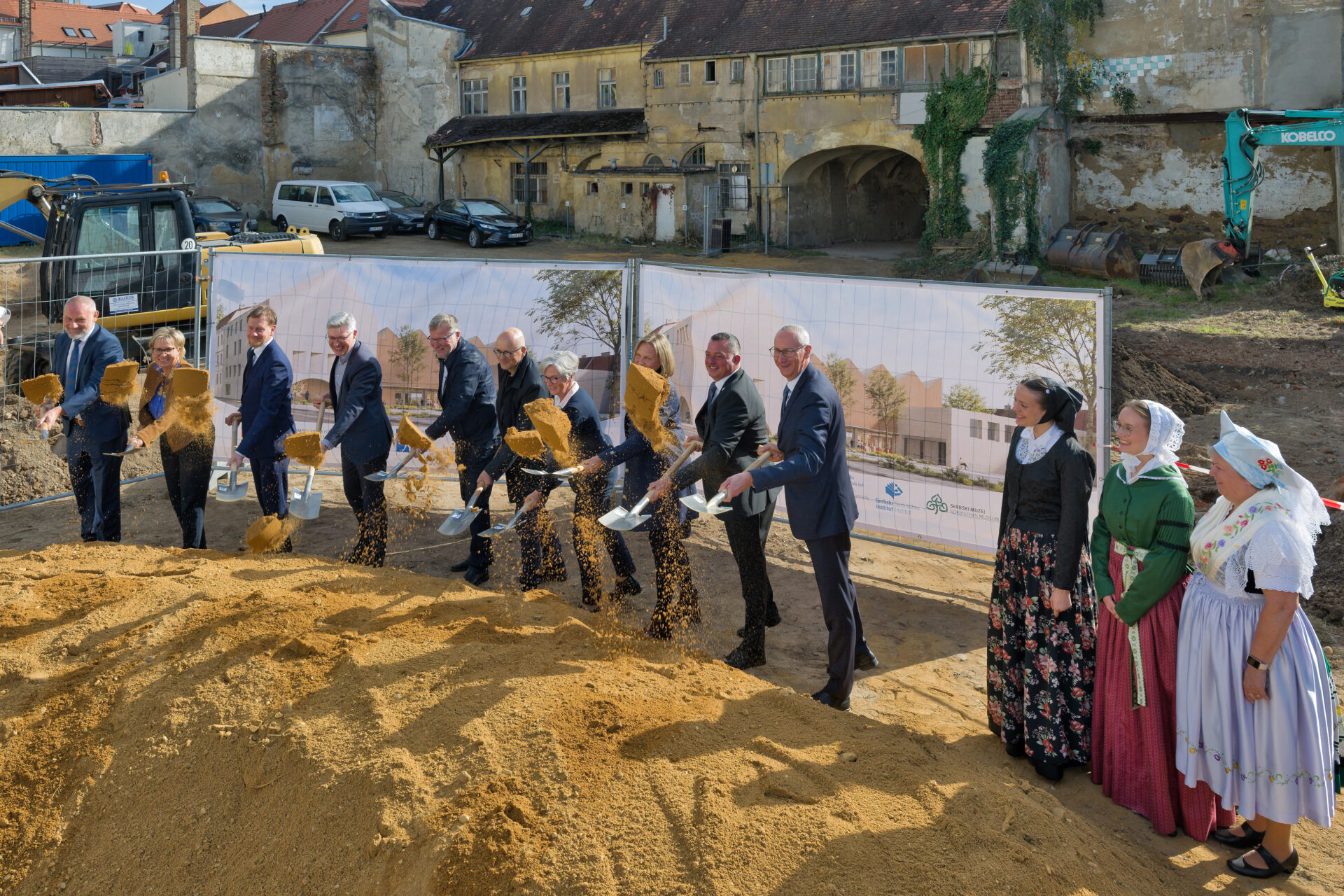 mehrere Personen werfen mit Schaufel Sand in die Luft